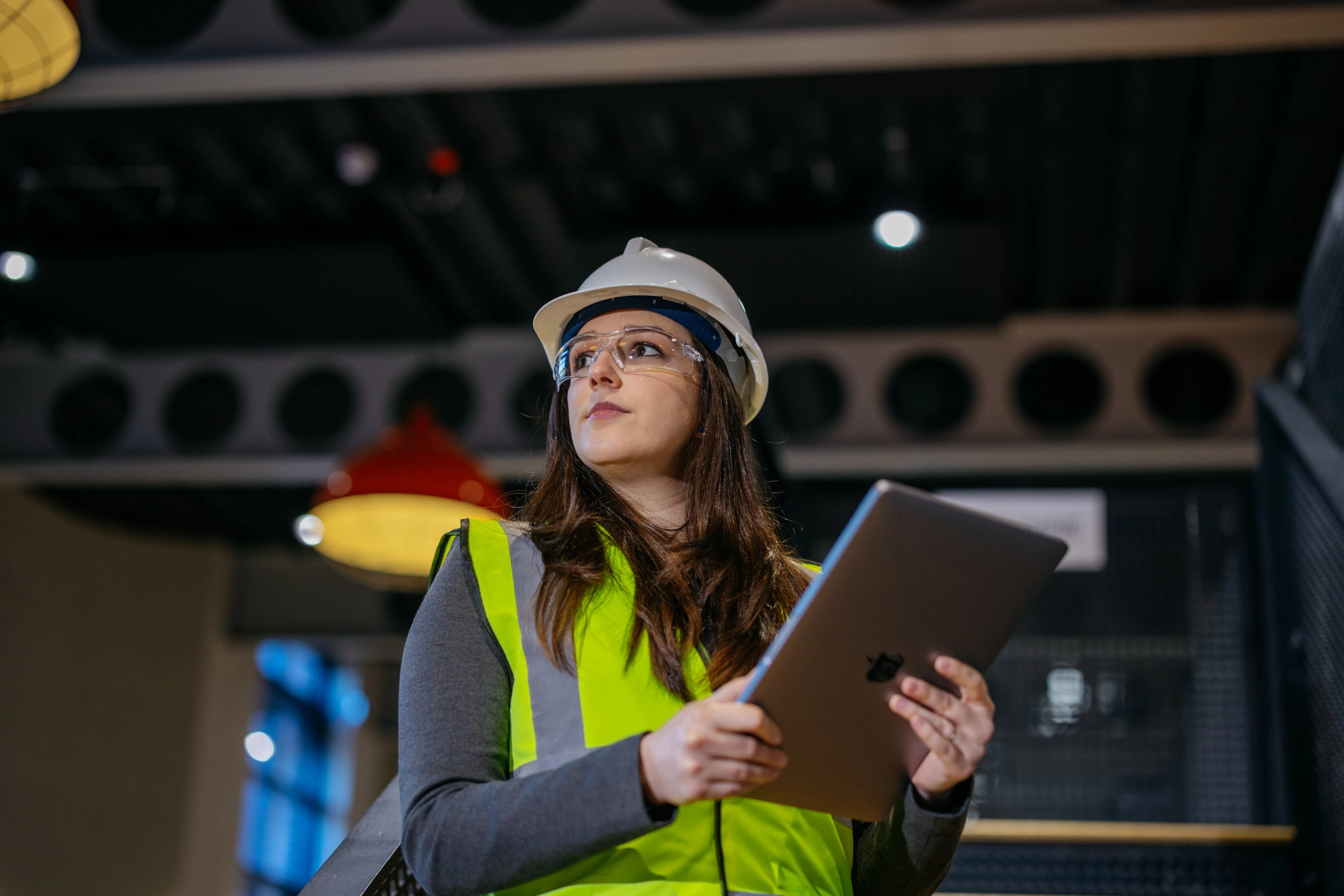 Industrial engineer reviewing energy data on a tablet at a manufacturing site