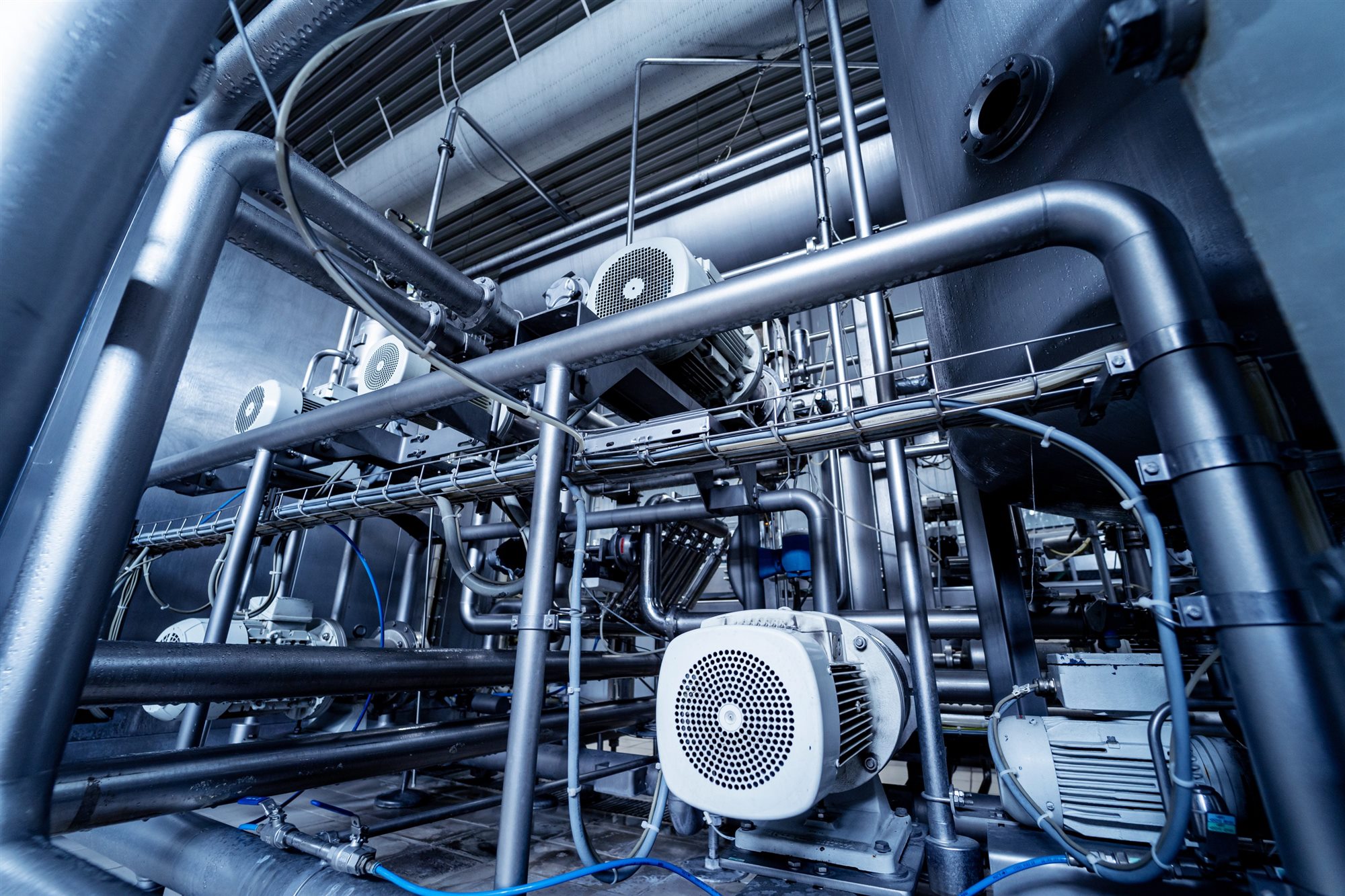 Stainless steel pipework, motors and process equipment inside a modern industrial plant