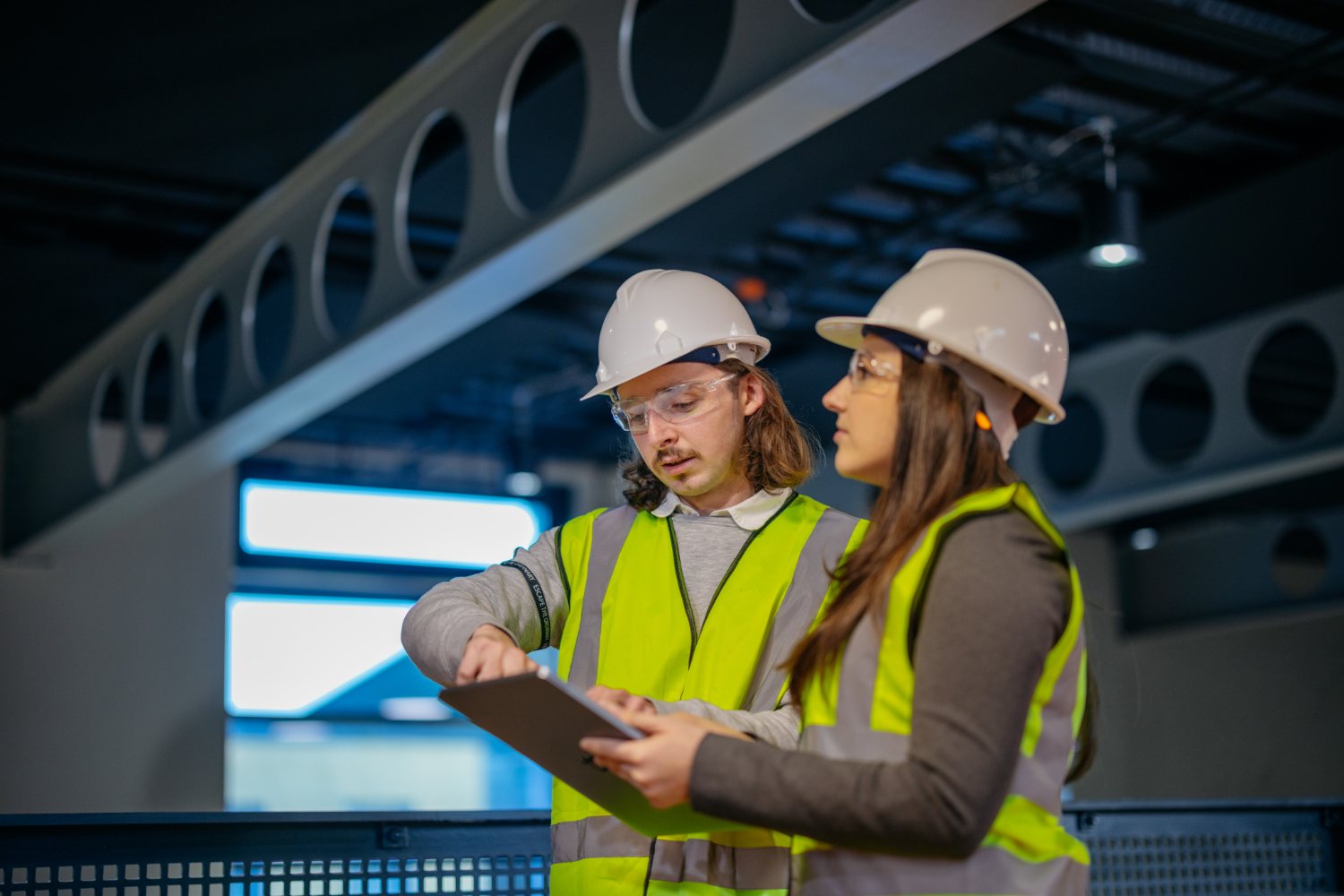 EM3 engineers reviewing energy data on a tablet in an industrial plant