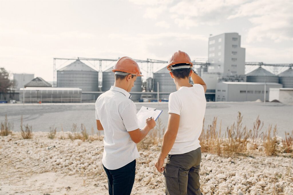 Engineers reviewing results in front of a large industrial processing facility