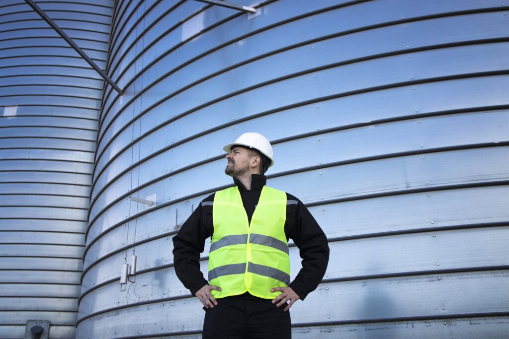 EM3 engineer on site beside an industrial storage tank