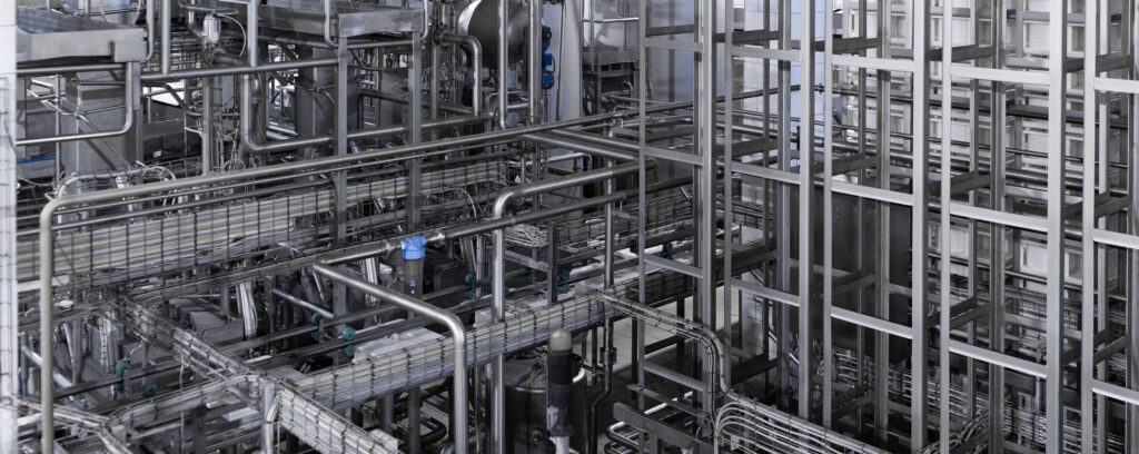 A complex maze of stainless steel pipework across an industrial facility