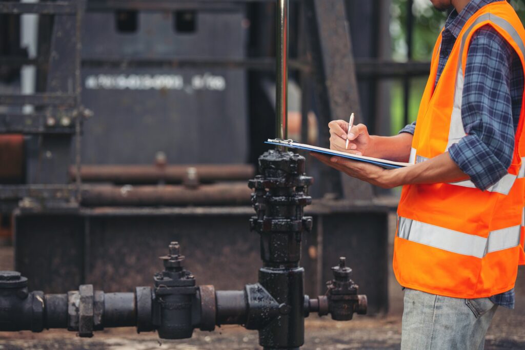EM3 engineer auditing industrial valve and pump equipment with a clipboard on site