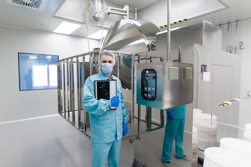 Engineer in protective uniform beside a large steel process asset with a control panel