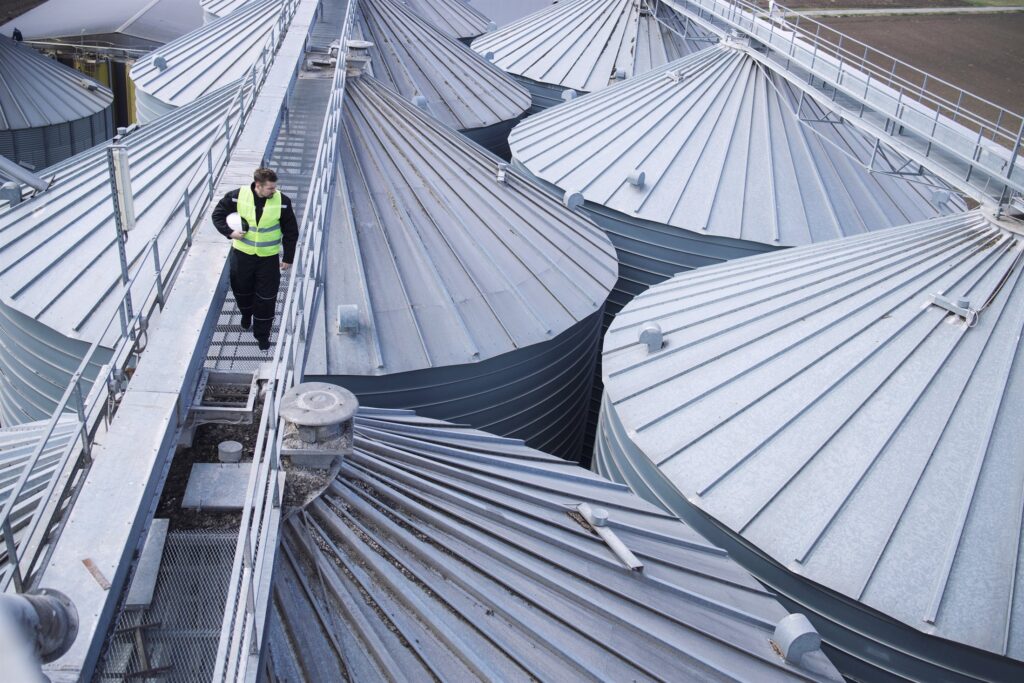 Engineer on a gantry inspecting rows of large industrial storage tanks