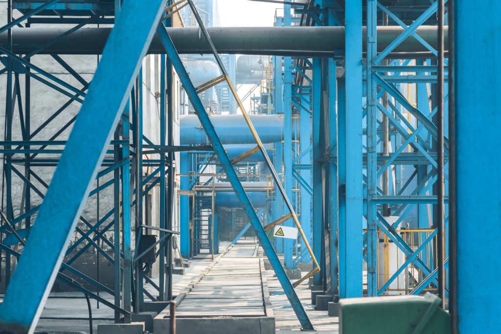 Walkway through a complex multi-system industrial plant with blue steelwork and pipework