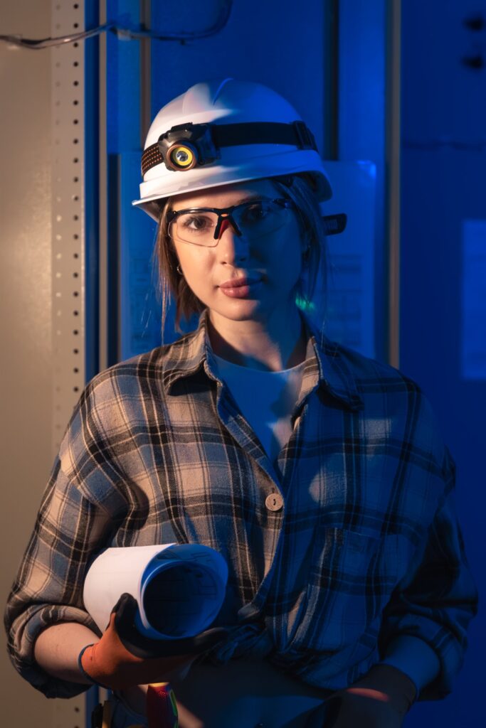 EM3 engineer with a system blueprint beside industrial switchgear