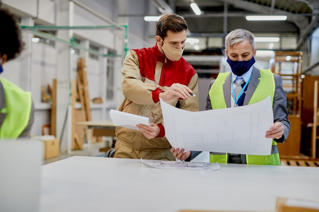 Workers analysing technical plans in a factory