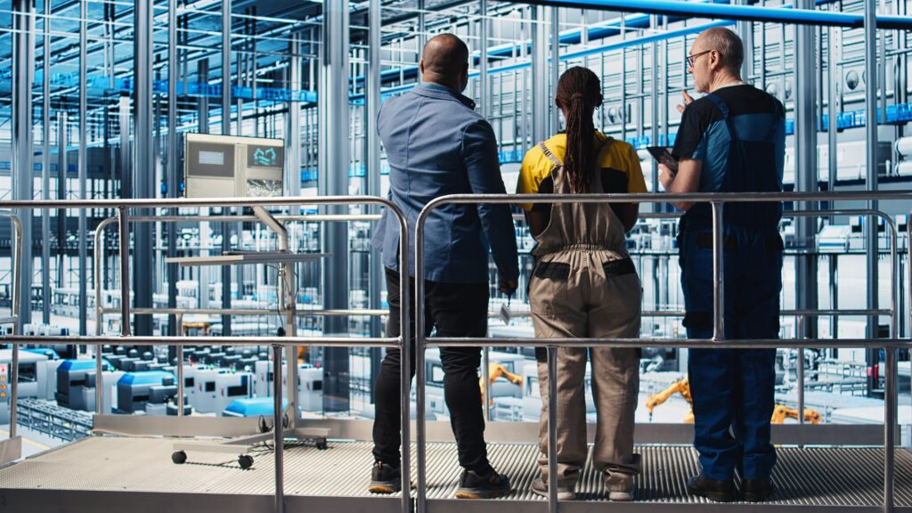An engineer on an industrial platform overseeing installation work done by engineers below