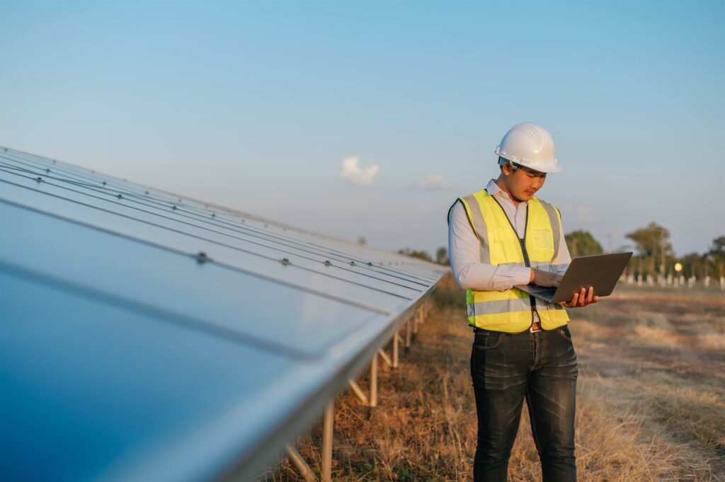 EM3 engineer with a laptop evaluating a solar installation on an industrial site