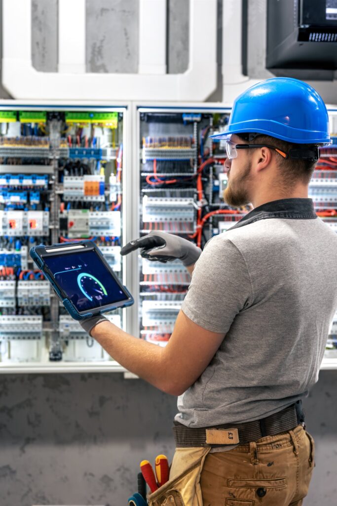 EM3 engineer reviewing energy data on a tablet at an industrial metering cabinet