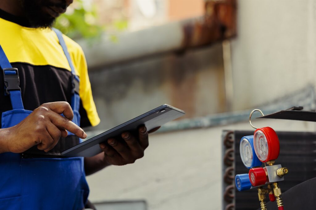 Engineer doing leak checks and fault-finding on an air-conditioning system and recording findings