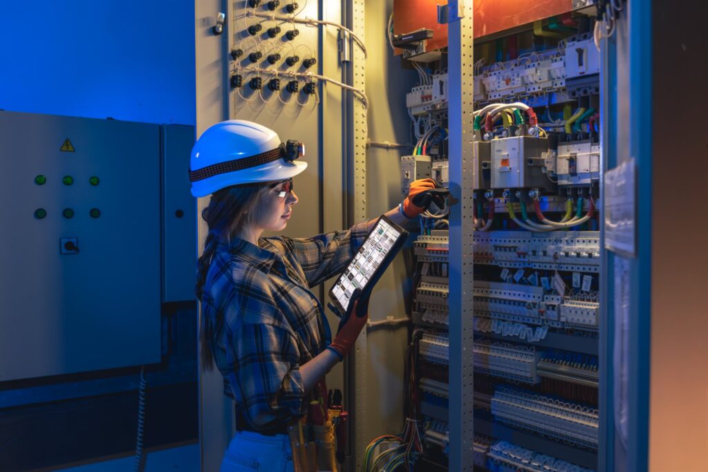 EM3 engineer auditing industrial switchgear with a tablet on site