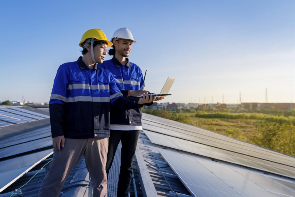 Engineers reviewing results beside an installed rooftop solar array on a factory
