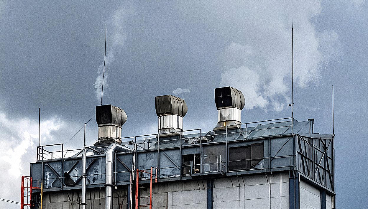 Industrial rooftop plant and ventilation systems under a heavy grey sky