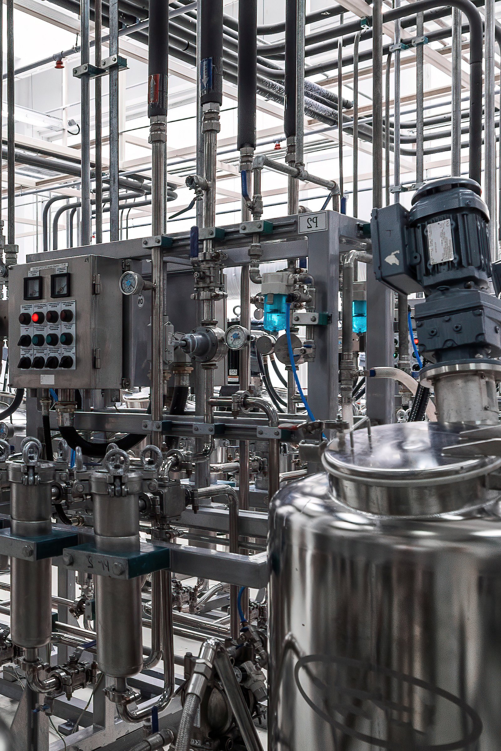 Stainless steel process vessels with agitators and a control panel in a bright pharmaceutical production hall