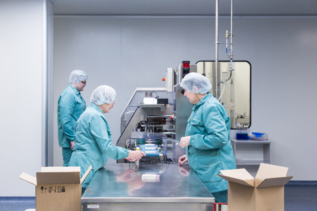 Pharmaceutical technicians in protective clothing working in a sterile production area