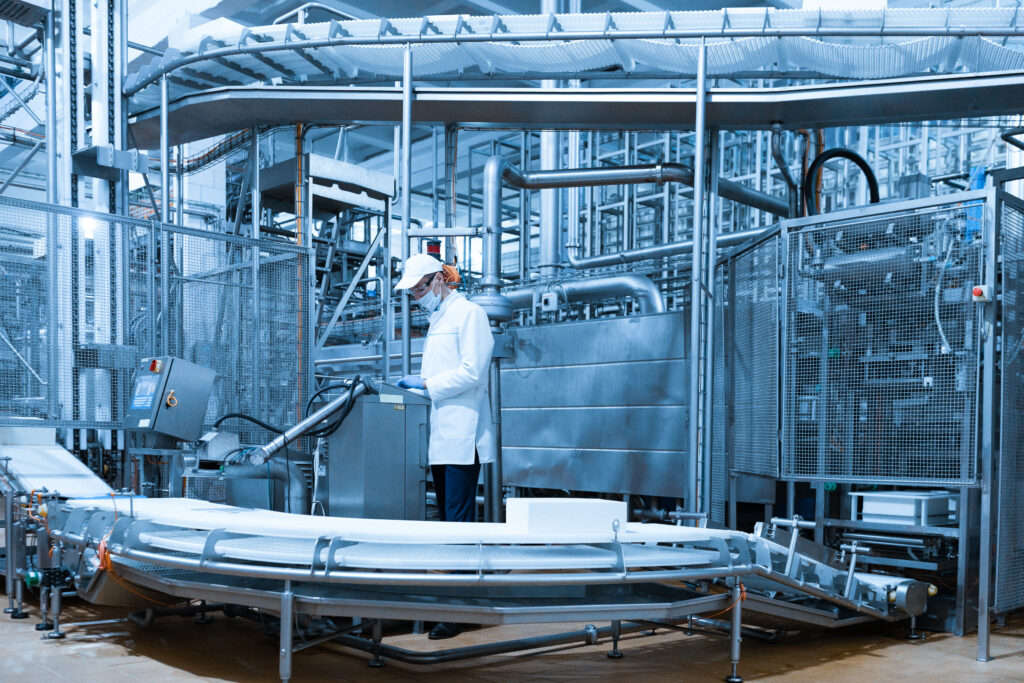 A technologist setting up a production line beside a digital screen in a dairy factory