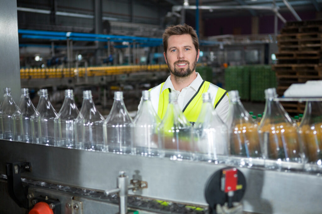 A worker beside a bottling production line in a juice factory