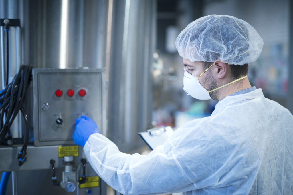 A technologist in protective uniform operating an industrial machine on a production line