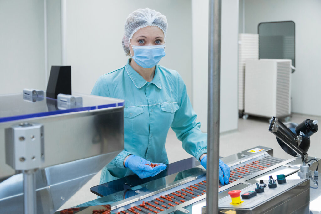 Operator in protective clothing running a tablet production line in a sterile pharmaceutical cleanroom