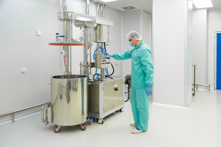 Operator in protective clothing using a control panel in a sterile pharmaceutical production area