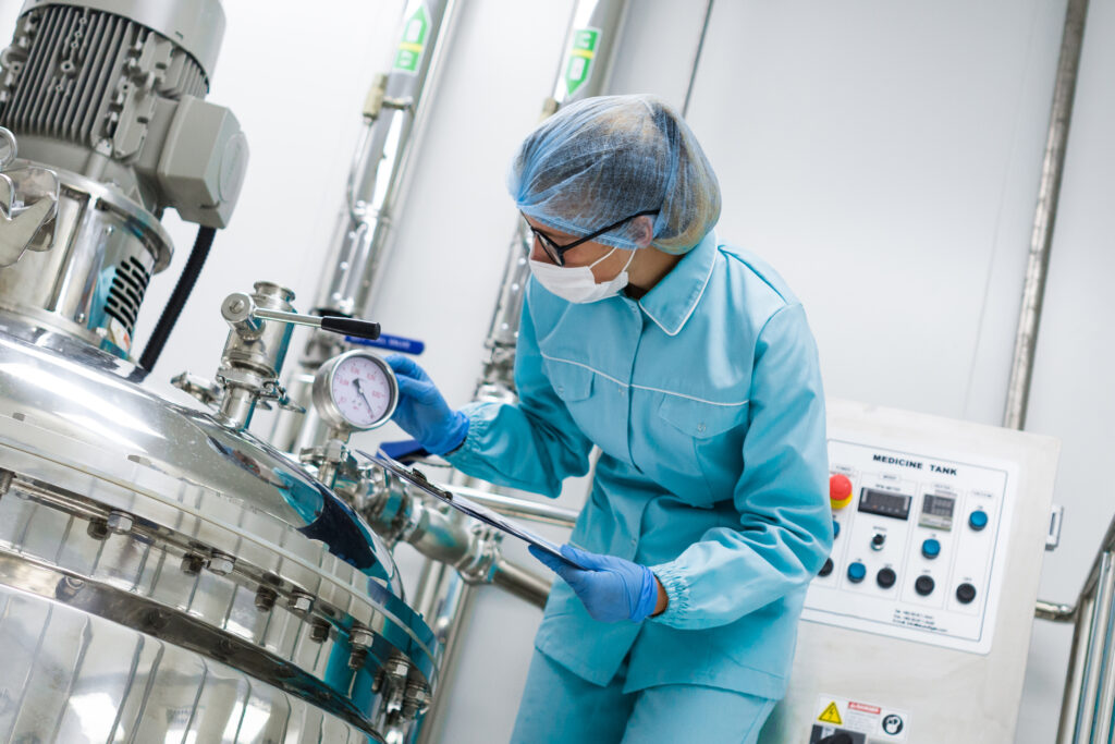 Operator checking a pressure gauge on a process vessel in a pharmaceutical manufacturing cleanroom